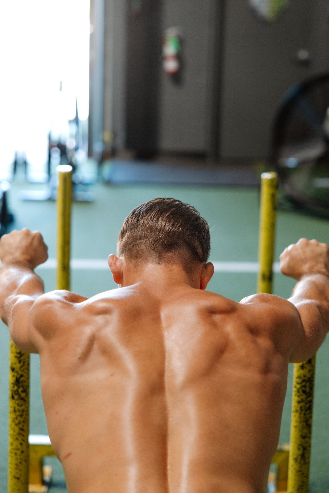Athlete mid-set on parallel bars, back to camera